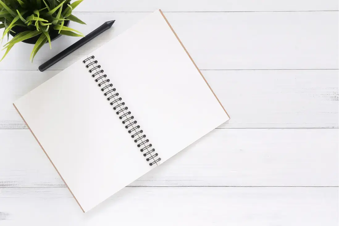 Taccuino aperto su superficie chiara, simbolo di semplicità e minimalismo nel design